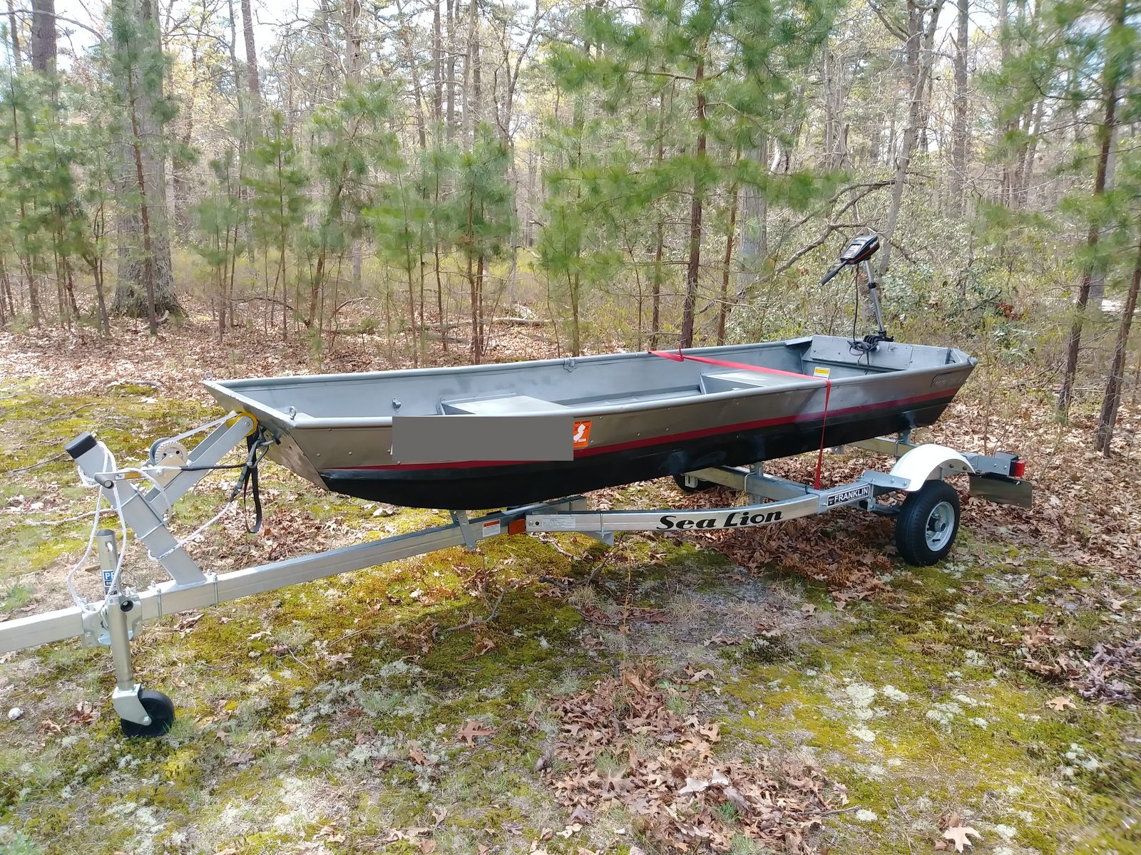 Finished boat on its new trailer in the woods, registration on the bow